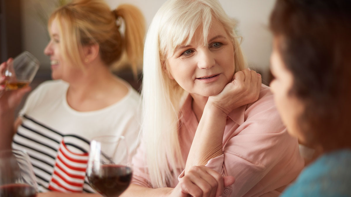 Woman looking shocked while talking to another, illustrating a downgrade by boyfriendu2019s mom and comparison to his classy ex.