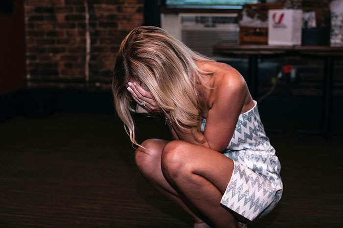 Woman crouching and crying alone at a bachelorette party, showing a bride’s dream bachelorette turning into a lonely cry-fest. Woman crouching and crying alone at a bachelorette party, showing a bride’s dream bachelorette turning into a lonely cry-fest.