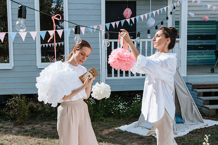 Two women preparing decorations outdoors for a bride’s dream bachelorette with strict rules before the party begins. Two women preparing decorations outdoors for a bride’s dream bachelorette with strict rules before the party begins.