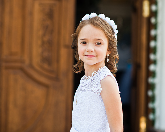 Young girl in white dress and floral headband standing near wooden door, related to Disneyland wedding news case. Young girl in white dress and floral headband standing near wooden door, related to Disneyland wedding news case.