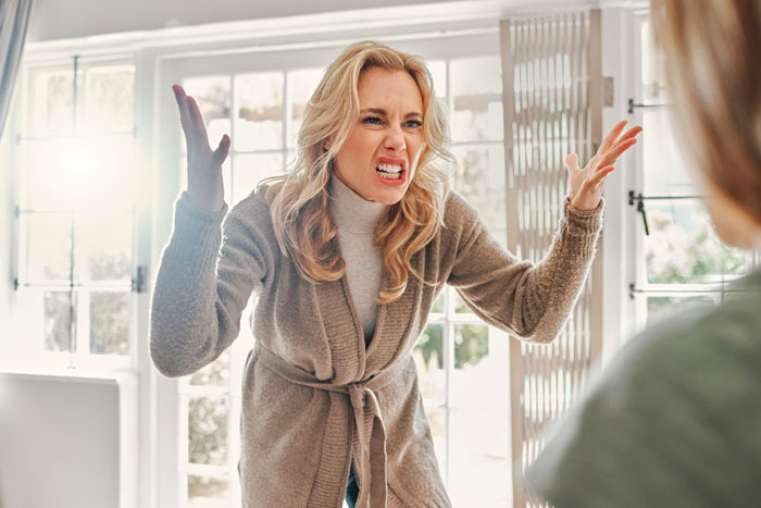 Angry woman confronts another person indoors, illustrating tension from brother’s lie to CPS affecting sister’s life. Angry woman confronts another person indoors, illustrating tension from brother’s lie to CPS affecting sister’s life.