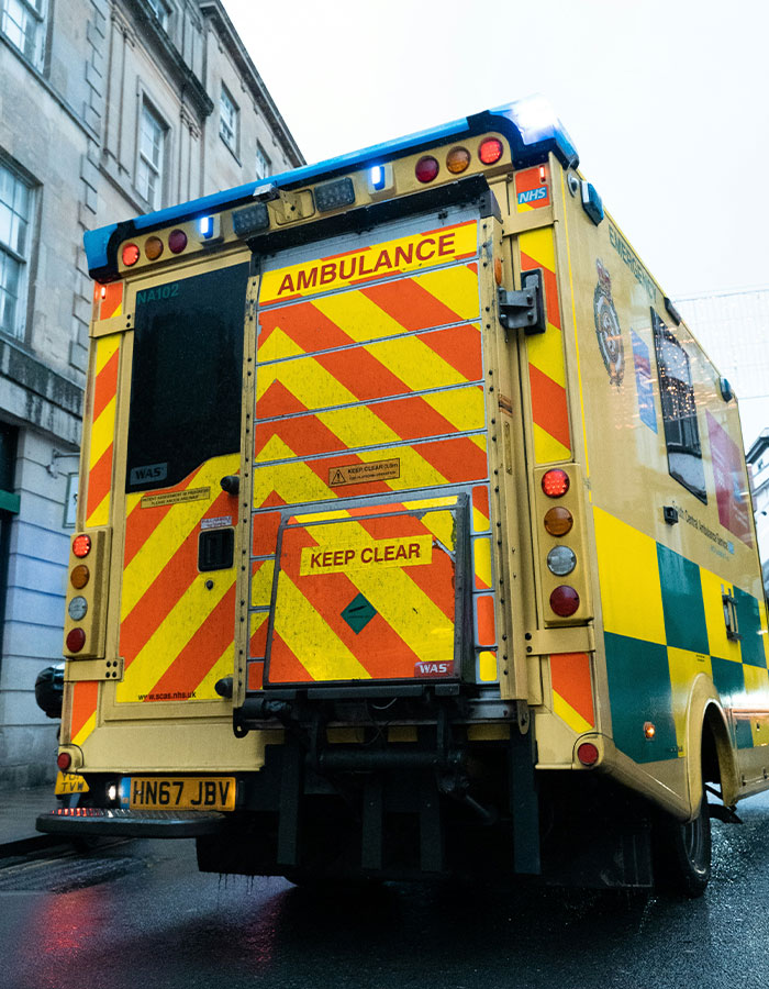 Yellow and green ambulance with flashing lights on a city street, related to excessive caffeine consumption incidents. Yellow and green ambulance with flashing lights on a city street, related to excessive caffeine consumption incidents.