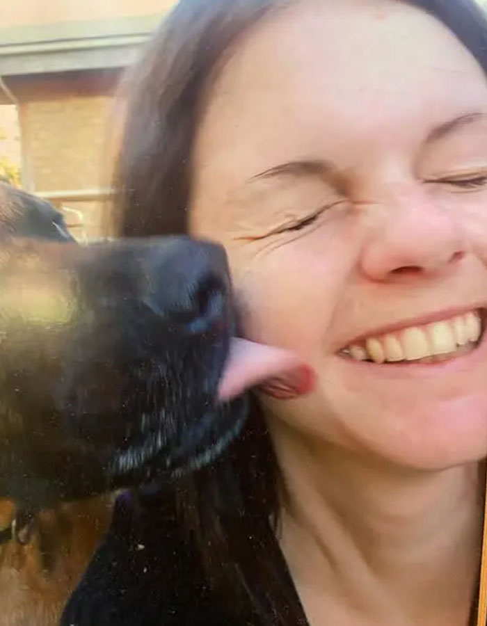 Australian woman smiling as dog licks her cheek outdoors, illustrating a personal moment before caffeine overdose news. Australian woman smiling as dog licks her cheek outdoors, illustrating a personal moment before caffeine overdose news.