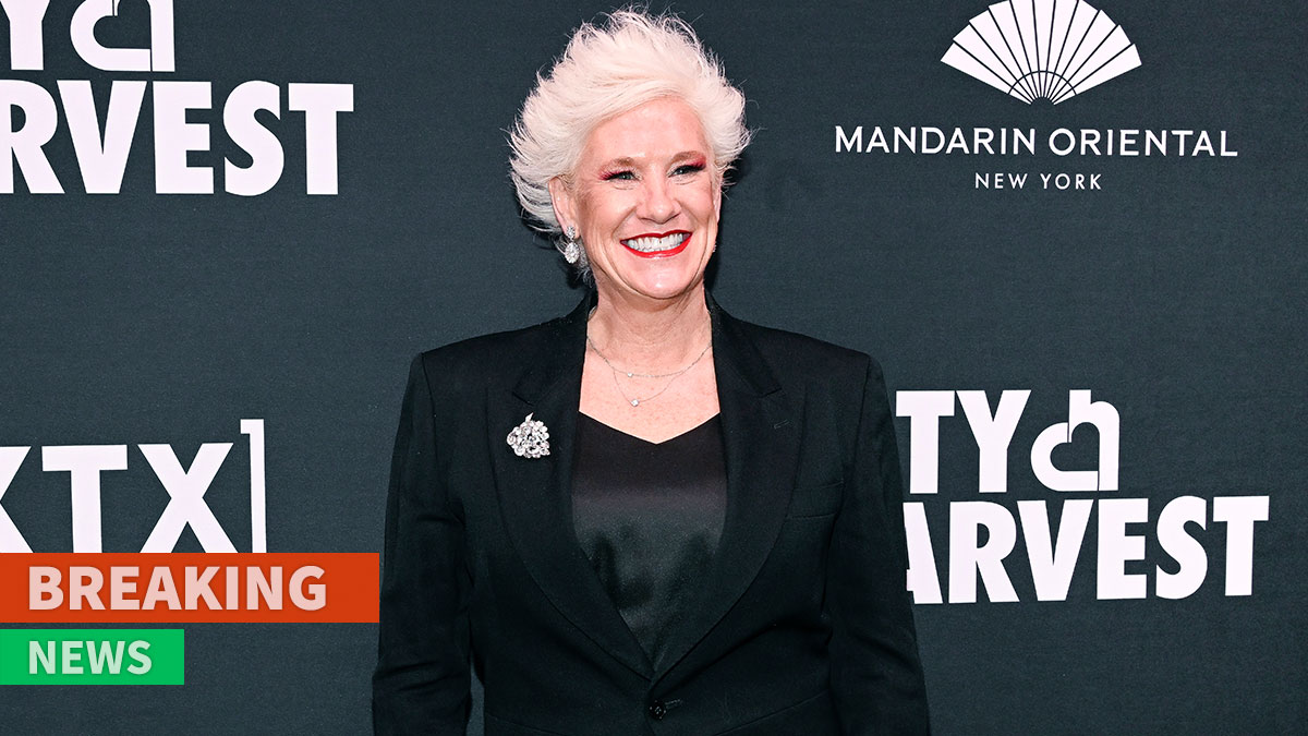 Celebrity chef Anne Burrell smiling at an event wearing a black blazer with white hair styled up.