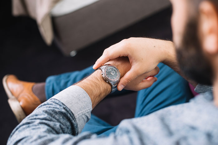 Man checking his watch while sitting, representing a man wanting to save money on dinner with coupon.