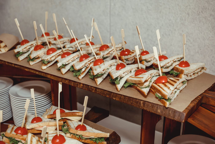 Tray of sandwiches garnished with cherry tomatoes, representing a man saving $100 on dinner with coupon.