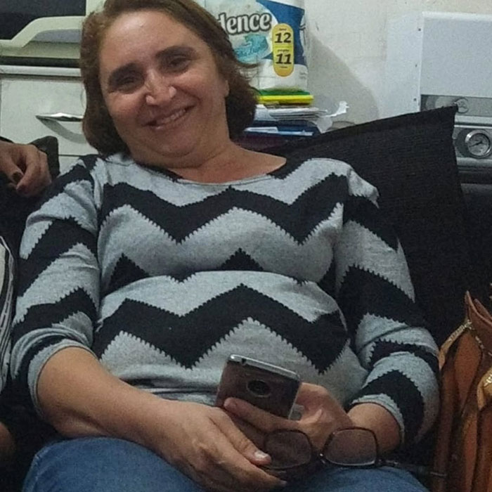 Woman sitting and smiling, holding a phone, representing before-and-after photos of bodybuilding champion transformation. Woman sitting and smiling, holding a phone, representing before-and-after photos of bodybuilding champion transformation.