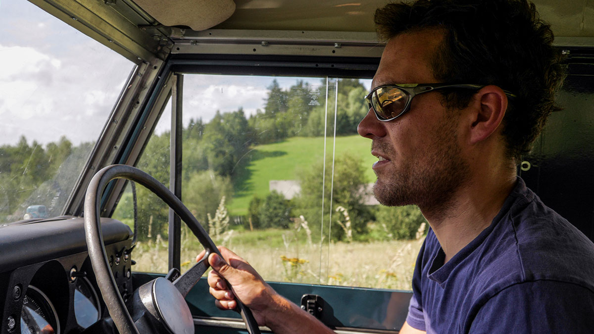 Man driving a 1972 Ford Bronco, chasing high school memories on a sunny day in the countryside.