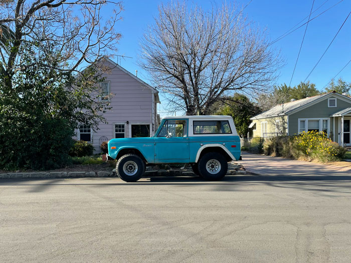 1972 Ford Bronco parked on a suburban street, surrounded by houses and leafless trees on a clear day 1972 Ford Bronco parked on a suburban street, surrounded by houses and leafless trees on a clear day