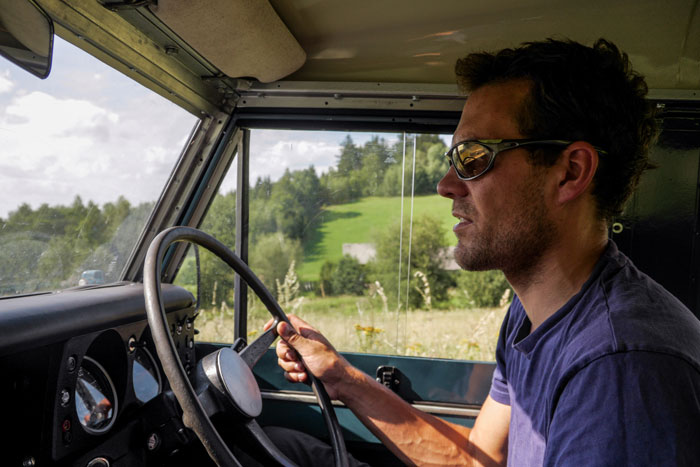 Man driving a vintage 1972 Ford Bronco in a countryside setting, chasing high school memories on a sunny day. Man driving a vintage 1972 Ford Bronco in a countryside setting, chasing high school memories on a sunny day.