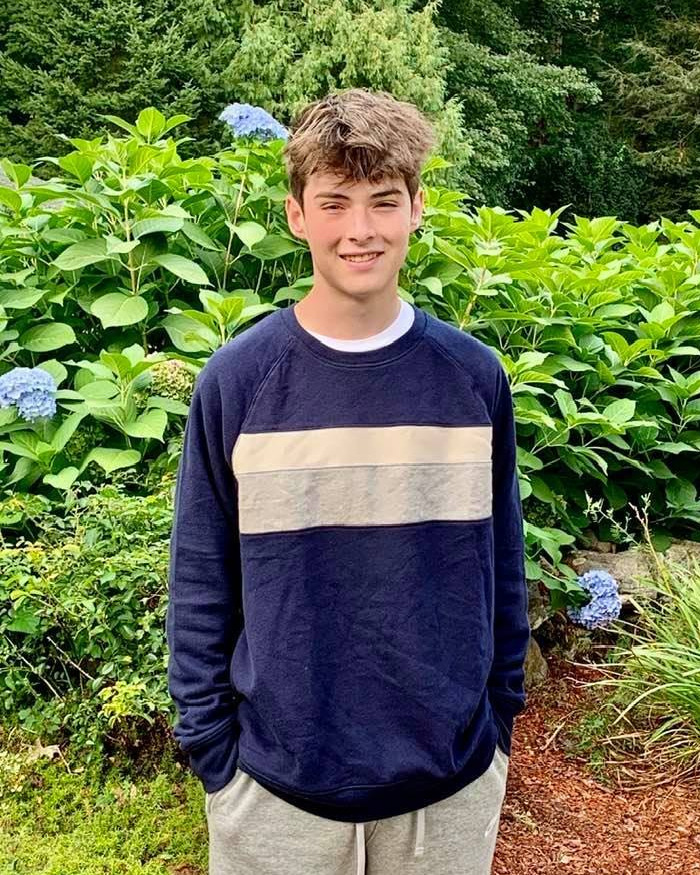 Young college student standing outside in garden wearing navy sweatshirt and gray sweatpants on a sunny day. Young college student standing outside in garden wearing navy sweatshirt and gray sweatpants on a sunny day.