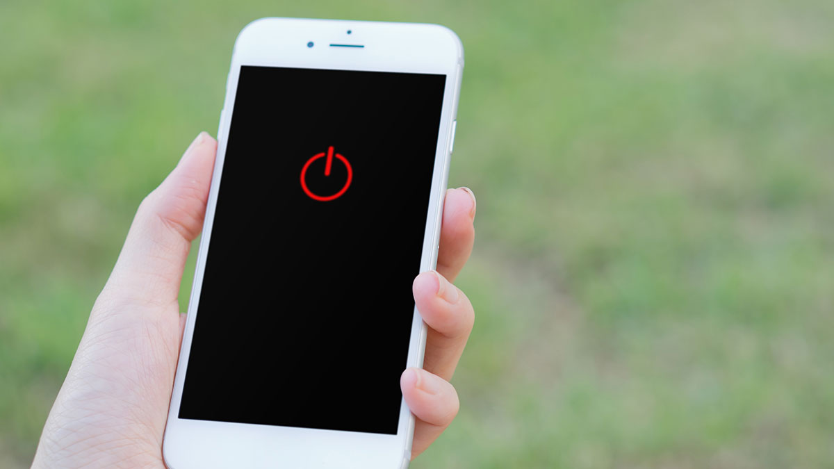 Hand holding white smartphone with red power symbol on screen, illustrating employee complies with company rules concept.