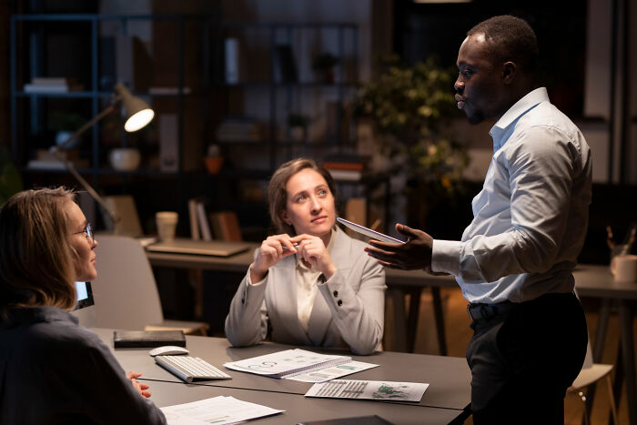Three corporate colleagues in a meeting discussing documents, illustrating ways to call out lies politely or directly.
