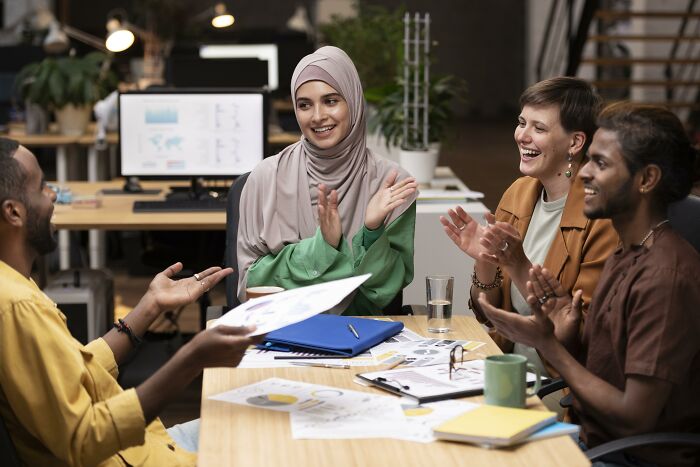 A diverse group of corporate colleagues discussing and sharing ideas in an office, displaying teamwork and communication.
