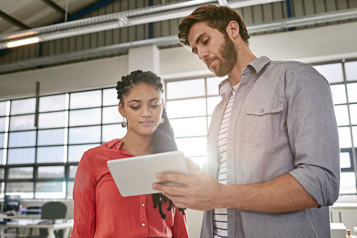 Two corporate colleagues reviewing information on a tablet, illustrating ways to call out corporate pals’ lies.
