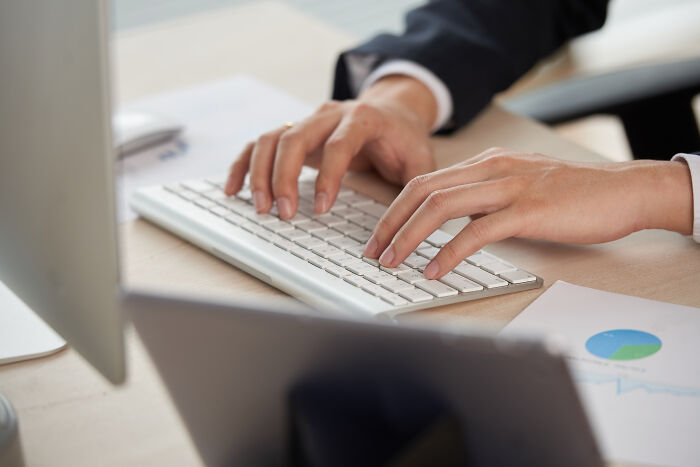 Person in business attire typing on a keyboard, illustrating ways to call out corporate pals’ lies politely or rudely.