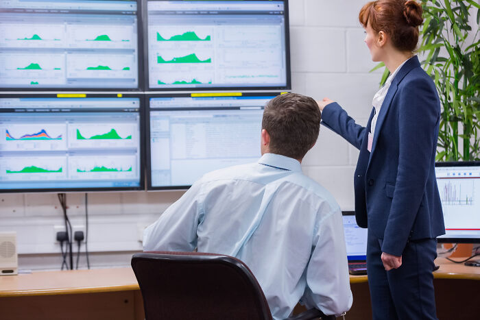Two corporate colleagues reviewing data on multiple screens, illustrating ways to call out corporate pals’ lies.