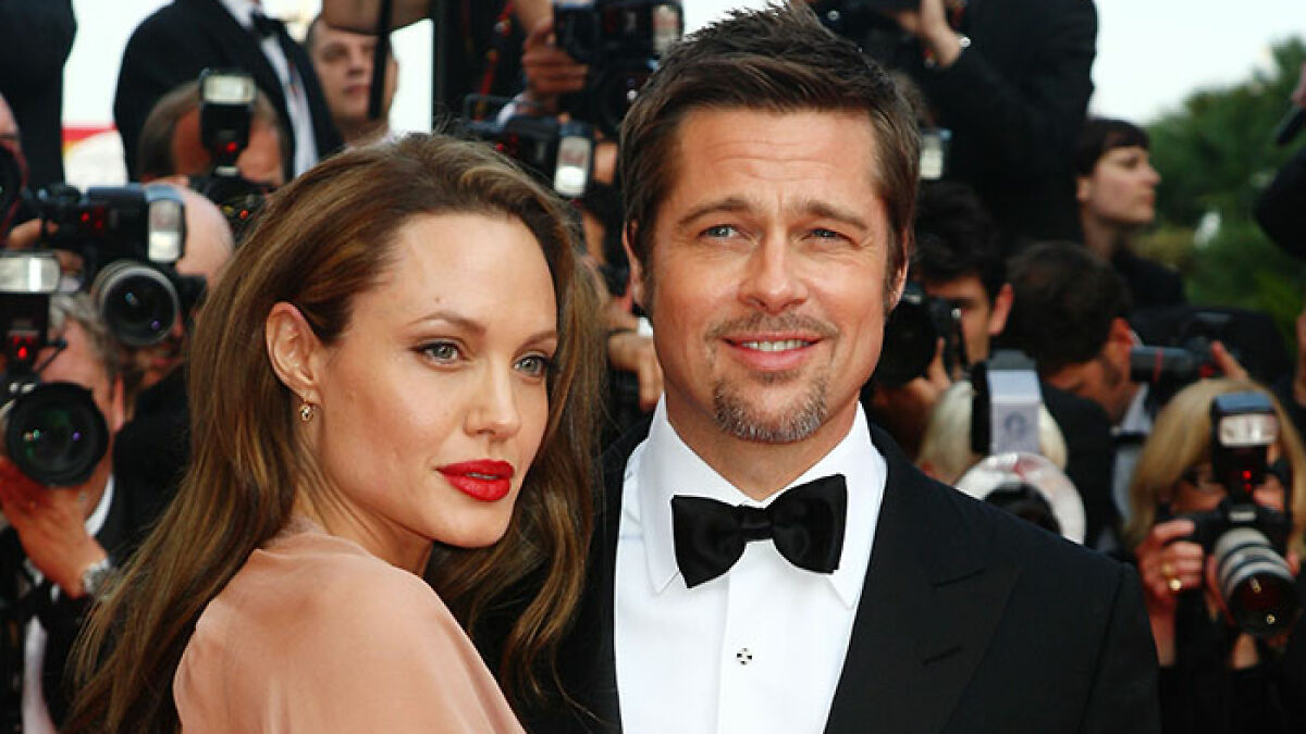Brad Pitt posing on the red carpet with Angelina Jolie while photographers capture the moment at a formal event.