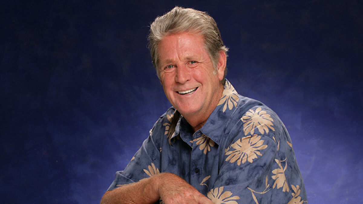 Smiling older man wearing a blue floral shirt is pictured, representing the Beach Boys legendary co-founder and musical genius.