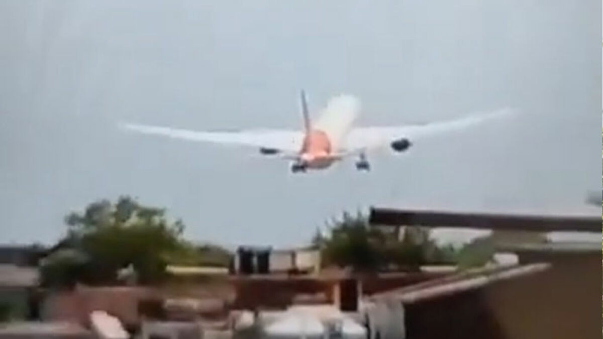 Airplane with unusual take-off captured mid-flight above buildings, raising expert concerns of evil intent and crash risk.