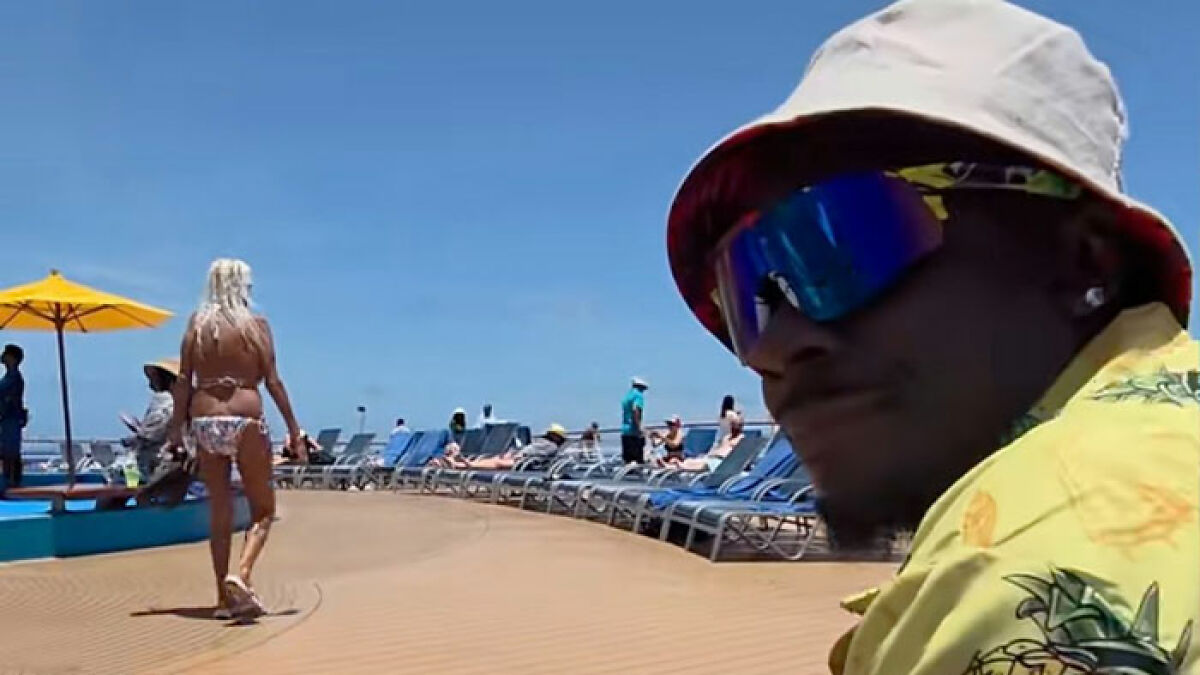 Cruise passenger wearing a pineapple shirt and bucket hat on deck, reacting to the x-rated meaning behind his clothing.