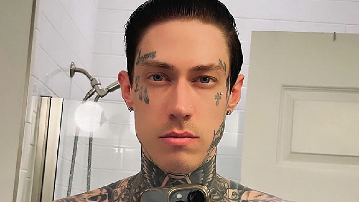 Trace Cyrus with facial and neck tattoos taking a mirror selfie in a bathroom, related to accusations and controversies.