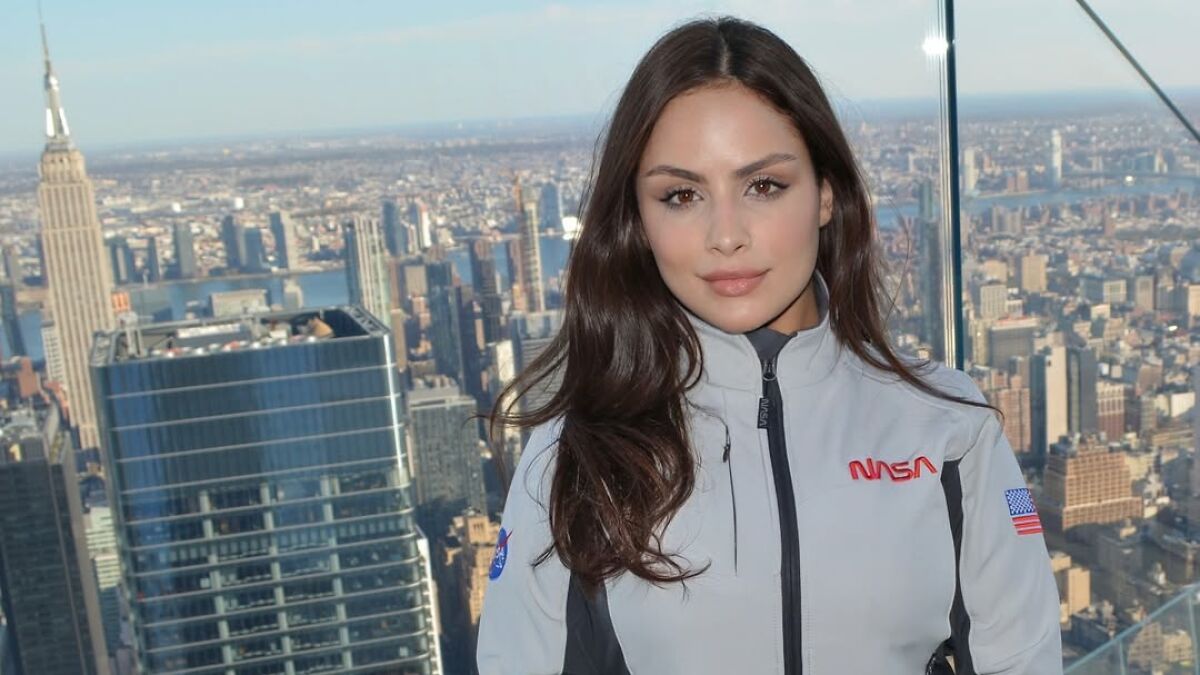 22-year-old woman in NASA jacket posing on rooftop with city skyline, related to astronaut and NASA response story.