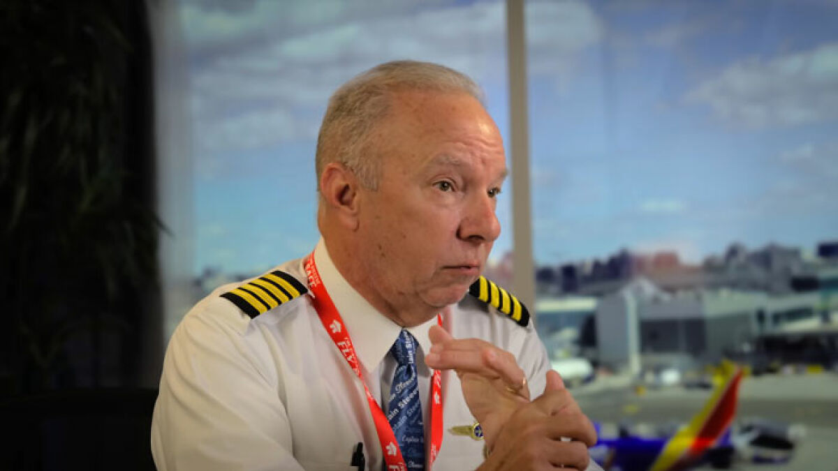 Experienced pilot in uniform explaining theory on simple mistake linked to tragic Air India crash in airport setting.