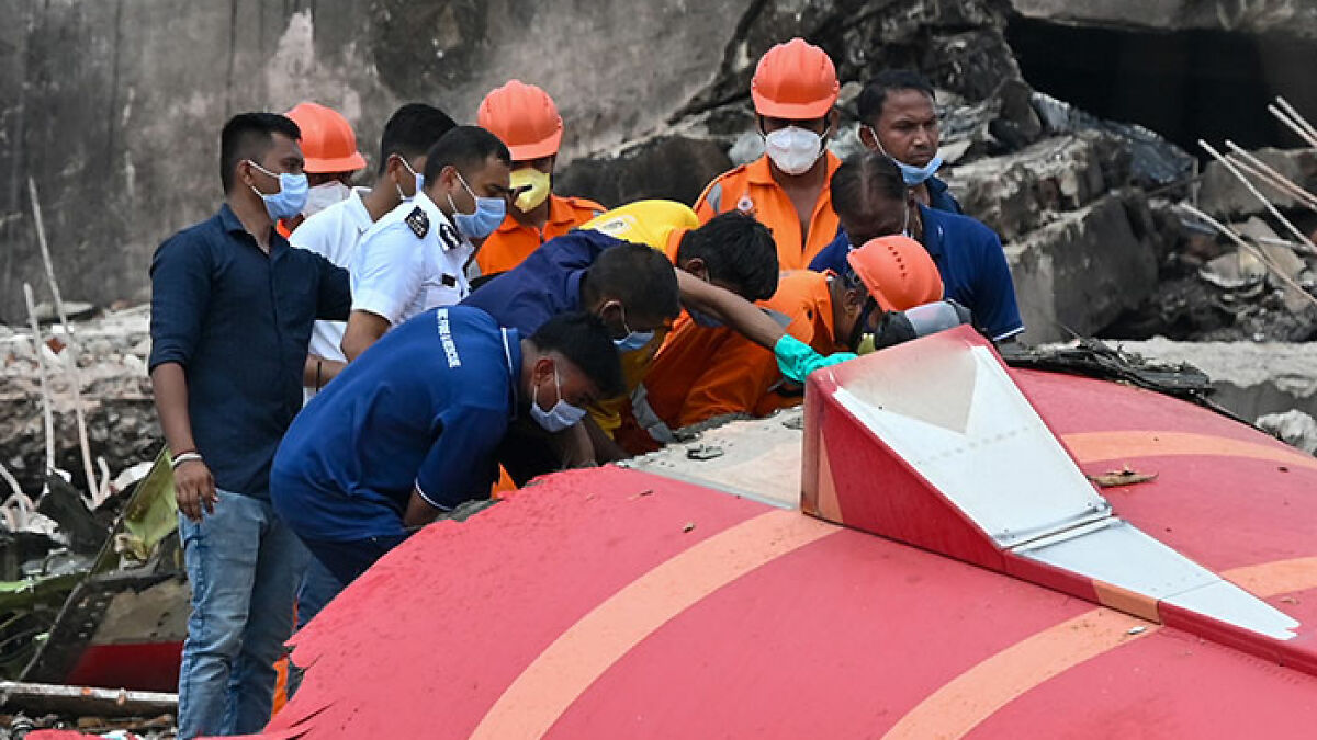 Rescue workers and young medical students wearing masks inspecting wreckage after Air India plane crashes into campus.