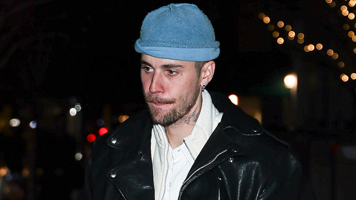 Justin Bieber looking somber in a blue hat and black leather jacket during a night outing raising concerns.