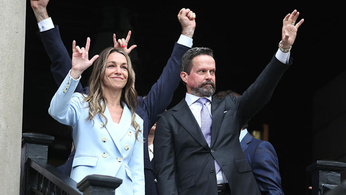 Karen Read celebrating acquittal in trial for slaying cop boyfriend, raising hands with supporters outside courthouse.