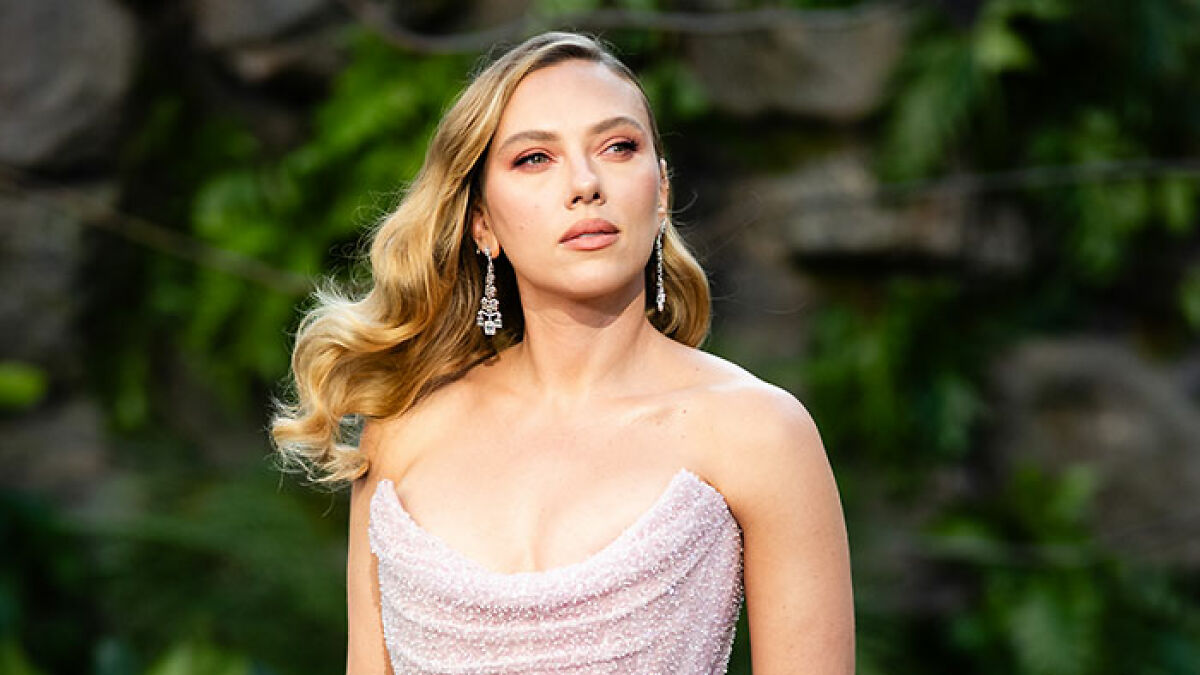 Scarlett Johansson stuns fans at premiere, wearing elegant gown with long earrings and soft wavy hair outdoors.