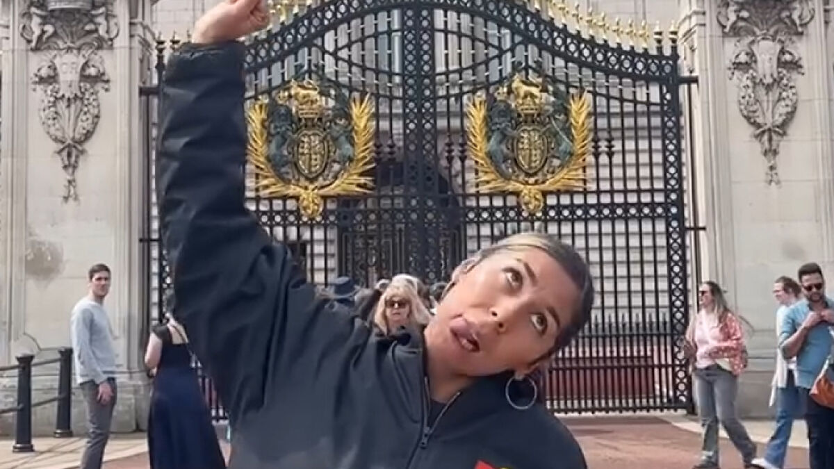Aboriginal artist performing provocatively in front of Buckingham Palace gates, sparking debate about King Charles controversy.