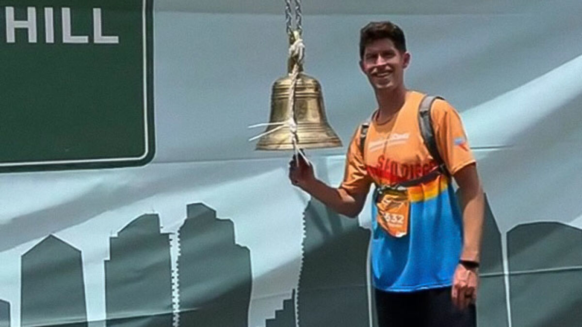 Man ringing a bell after completing a marathon with zero training and just 24 hours notice before the race.