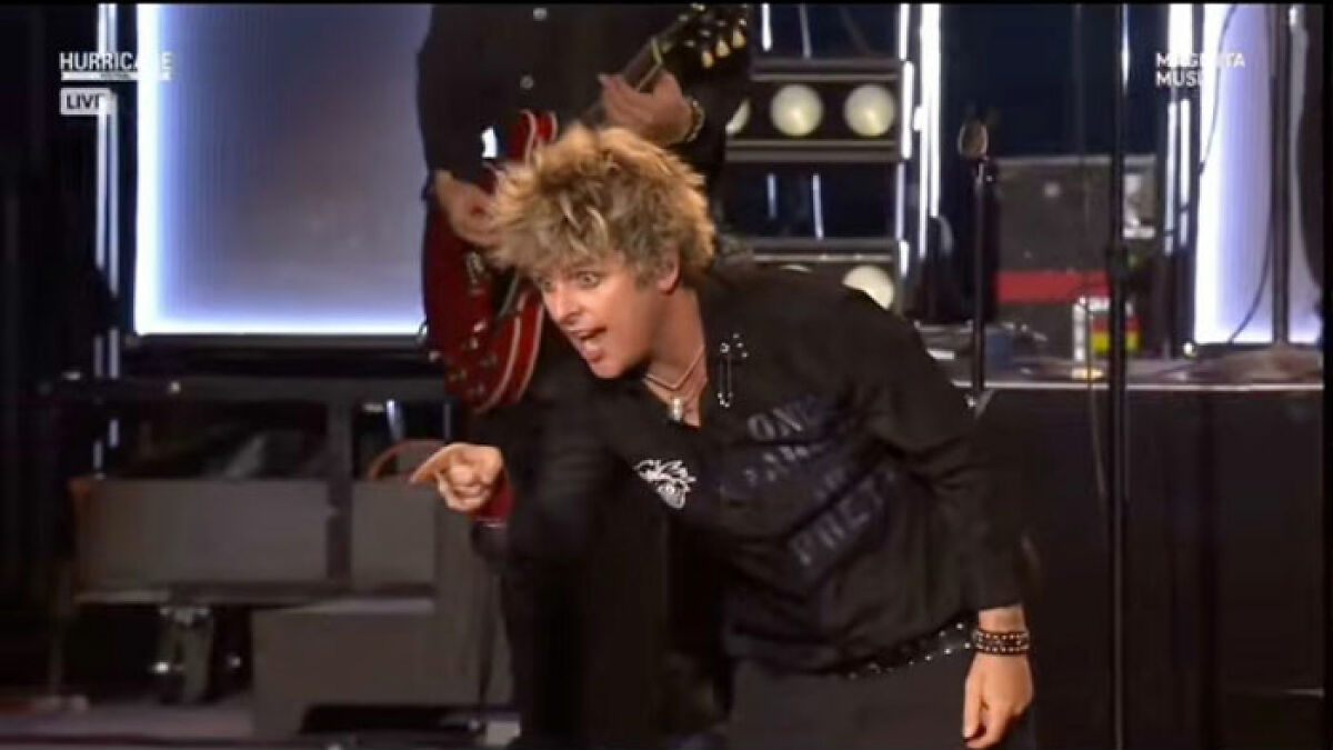 Green Day's Billie Joe Armstrong onstage pointing and confronting a rude fan during a live concert performance.