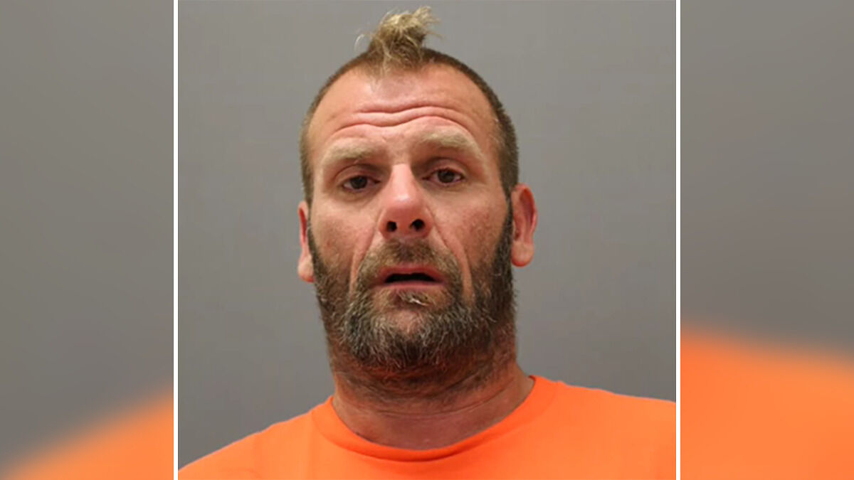 Mugshot of a man wearing an orange shirt linked to the case of a caring mother with a portion of jaw missing.