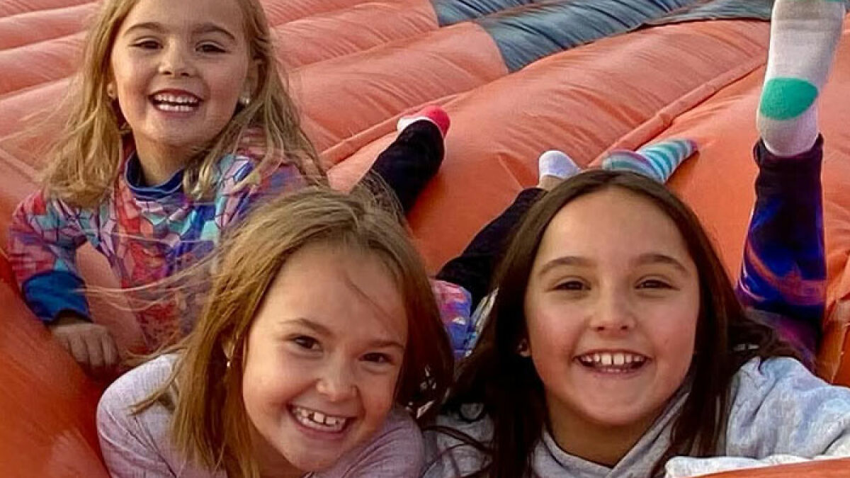 Three smiling young girls playing on an inflatable slide recalled in Travis Decker neighboru2019s weird encounter before incident.