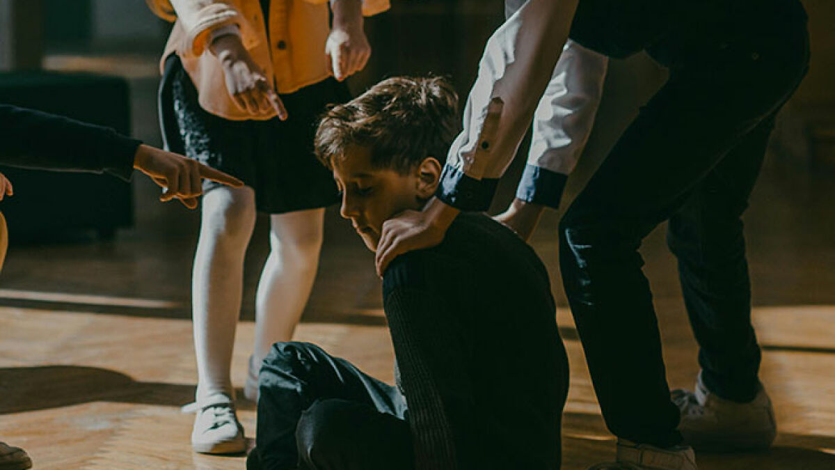 5th grade girls bullying boy at school, revenge plot implied, boy sitting on floor with distressed expression