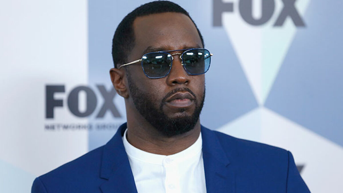 Diddy in blue suit and sunglasses at FOX event, related to court sketch artist trial coverage controversy.