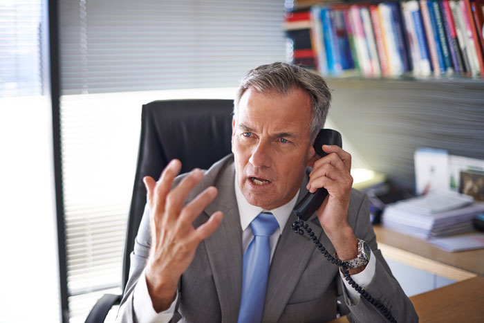 Man in office speaking on phone, expressing frustration while discussing colleague's sickness and workplace conflict. Man in office speaking on phone, expressing frustration while discussing colleague's sickness and workplace conflict.