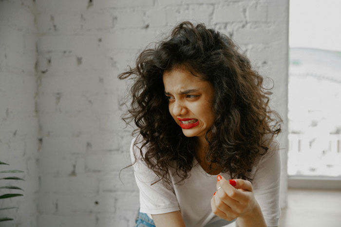 Woman in casual clothes grimacing with frustration, portraying coworker tea thief annoyance at work environment. Woman in casual clothes grimacing with frustration, portraying coworker tea thief annoyance at work environment.
