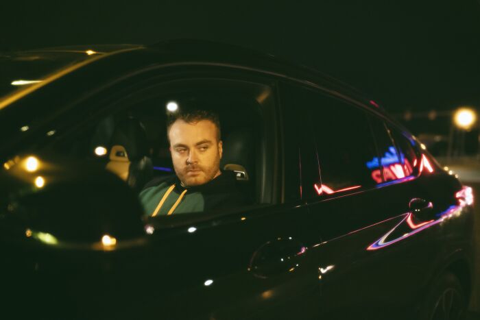 Man sitting inside a car at night with a concerned look, reflecting a creepy and chilling spot in the U.S.