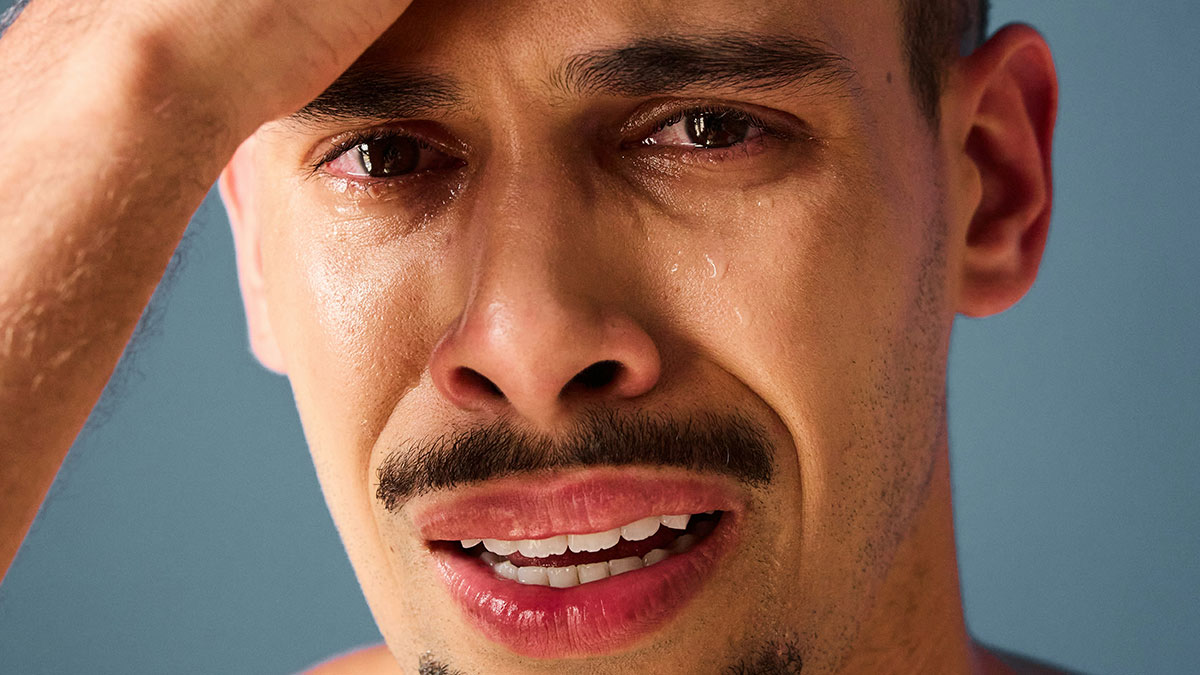 Man with tears streaming down his face showing emotional pain related to discovering kids are not biologically theirs