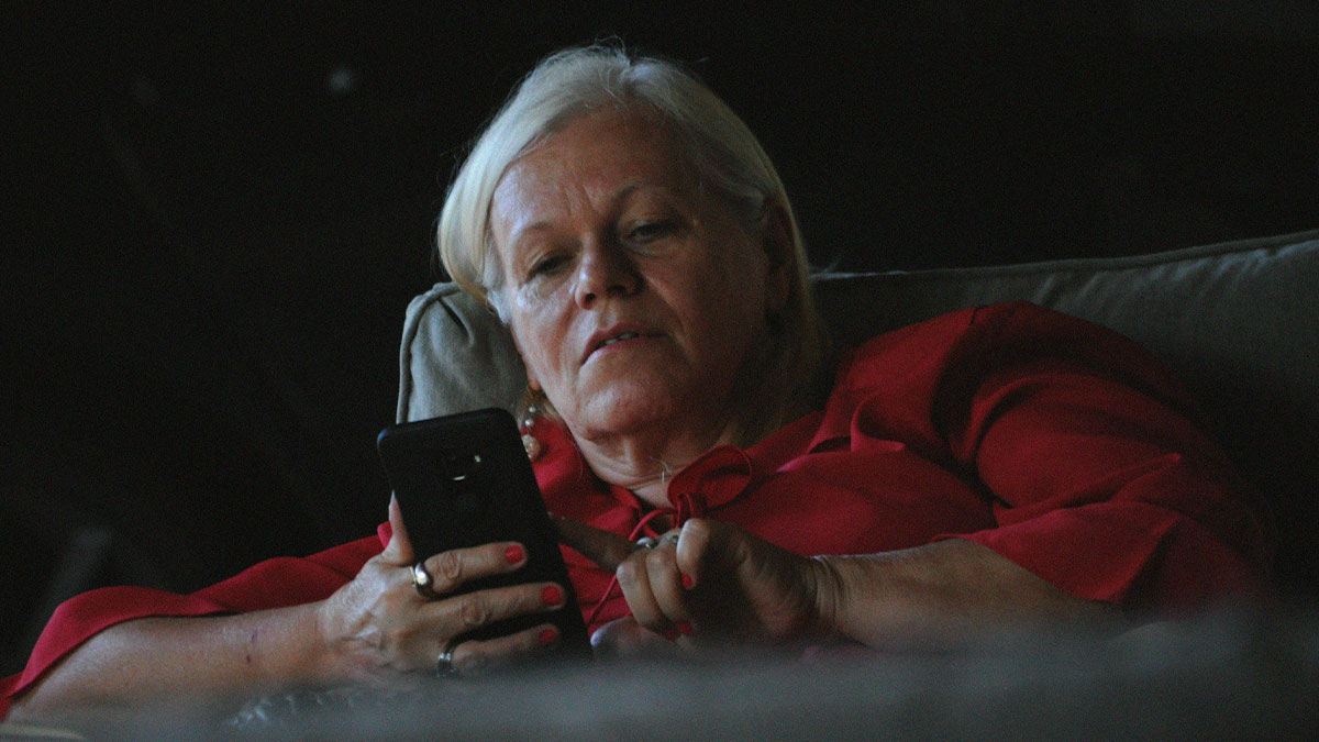 Concerned older woman in red shirt using phone, representing man seeking legal advice about lawsuit fears and $100K demand.