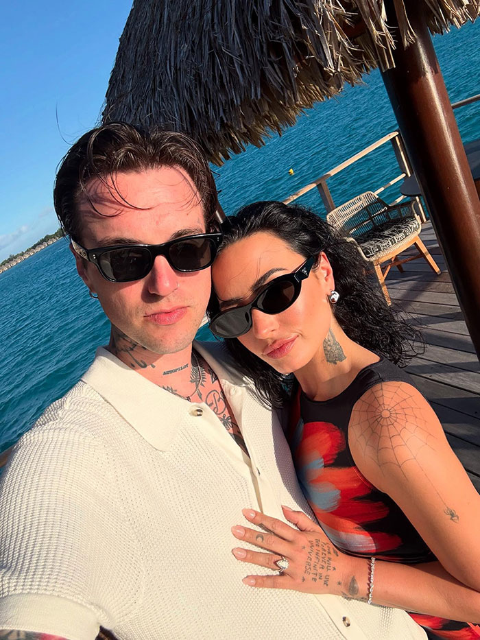 Demi Lovato and partner wearing sunglasses, posing on a sunny deck over blue water during a tropical honeymoon trip. Demi Lovato and partner wearing sunglasses, posing on a sunny deck over blue water during a tropical honeymoon trip.