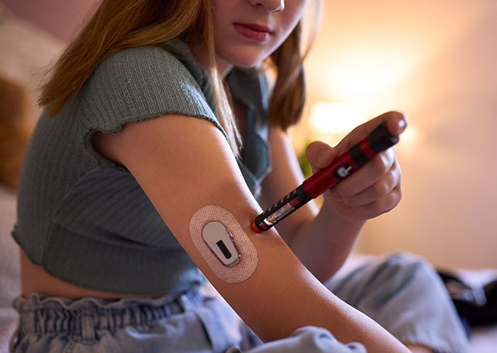 Woman administering insulin with a pen, prioritizing health over sister’s wedding photo aesthetic concerns. Woman administering insulin with a pen, prioritizing health over sister’s wedding photo aesthetic concerns.