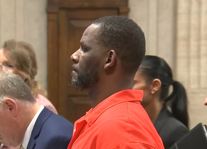R Kelly wearing an orange prison jumpsuit standing in court amid legal proceedings and public scrutiny. R Kelly wearing an orange prison jumpsuit standing in court amid legal proceedings and public scrutiny.