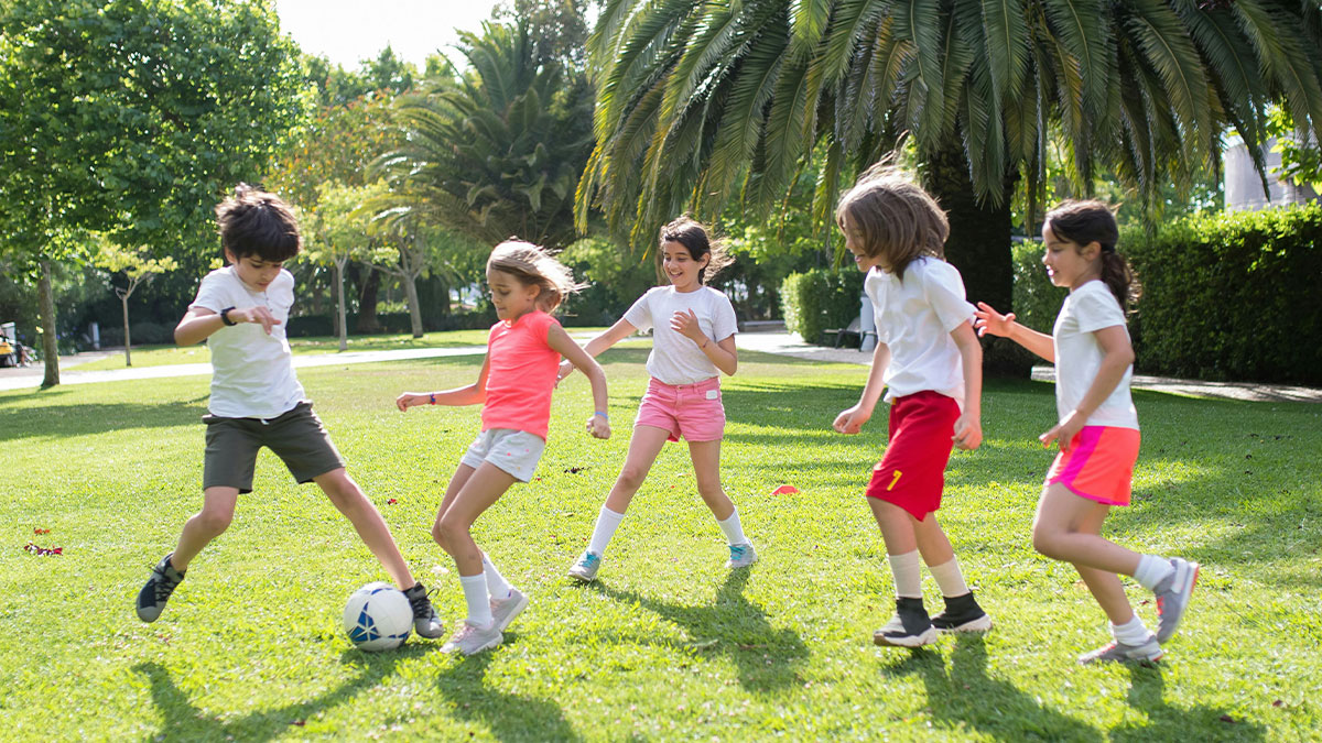 Children playing soccer on grass in a park during a family getaway, highlighting pediatrician boundaries and family dynamics.