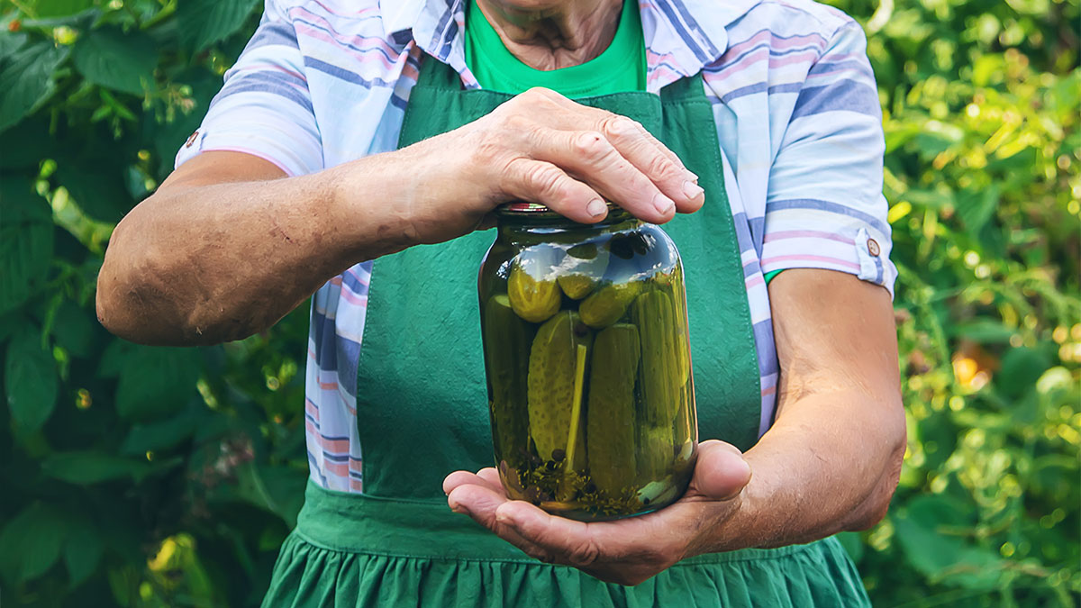 Person in a green apron holding a jar of pickles outdoors, illustrating times the police got dragged into nonsense.