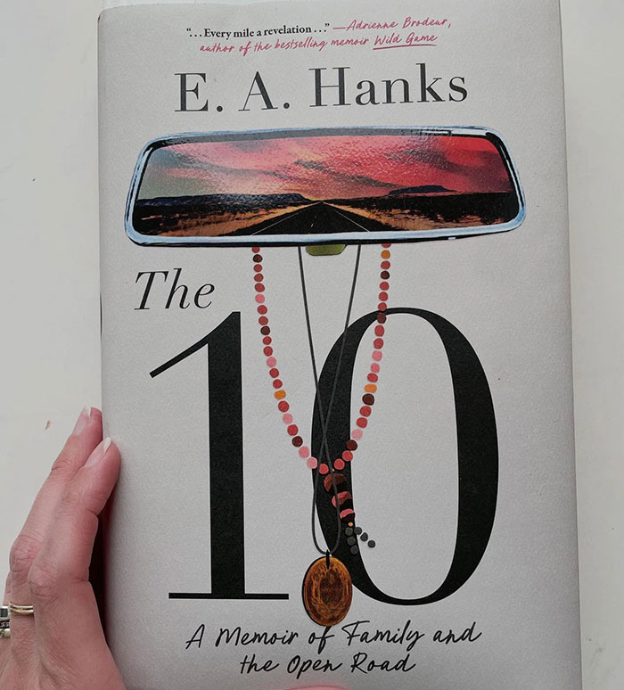 Book cover showing a memoir titled The 10 by E. A. Hanks with a rearview mirror reflecting a sunset road scene. Book cover showing a memoir titled The 10 by E. A. Hanks with a rearview mirror reflecting a sunset road scene.